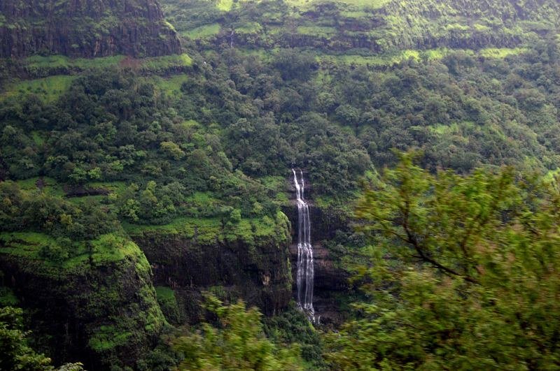 Monsoon waterfall in Lonavala surrounded by lush green hills and misty rainforest scenery.