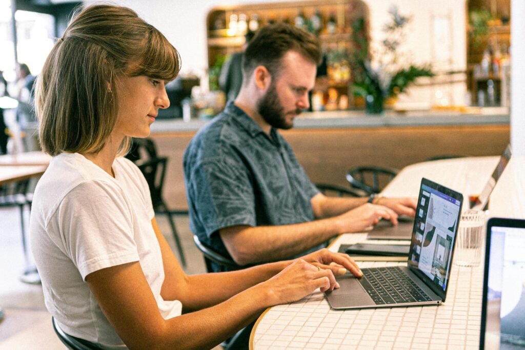 Two digital marketers working on laptops at a café.