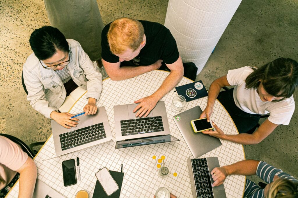 Digital marketing team discussing strategy around a table with laptops and charts