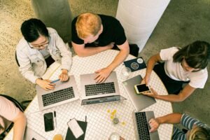 Digital marketing team discussing strategy around a table with laptops and charts