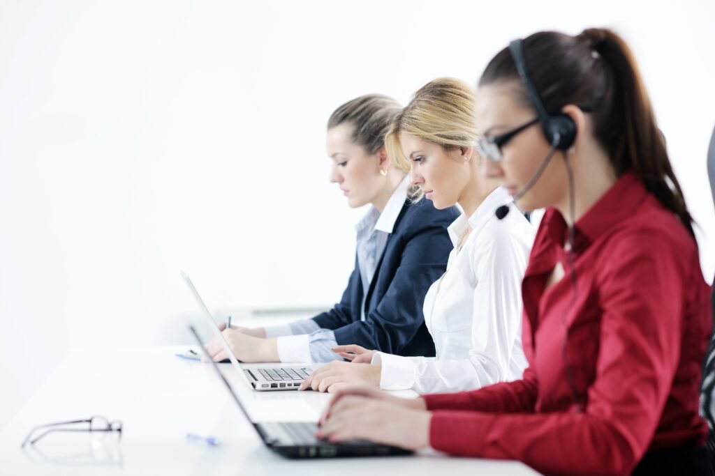 Pretty young business woman group with headphones smiling at you against white background