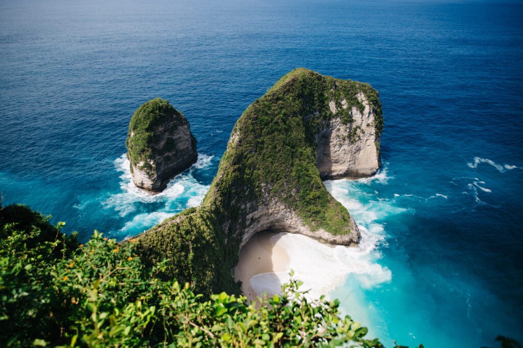 Aerial view of Kelingking Beach on Nusa Penida Island, Bali, featuring dramatic limestone cliffs and turquoise waters.