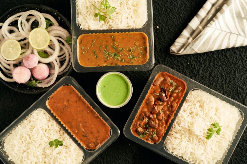 Indian food in takeaway containers with rice, dal, rajma, and salad – perfect for travelers missing home-cooked meals.