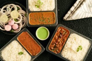 Indian food in takeaway containers with rice, dal, rajma, and salad – perfect for travelers missing home-cooked meals.